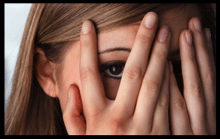 Girl covering her face with one eye looking between the fingers