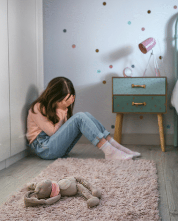 Girl in pink shirt crying in her room