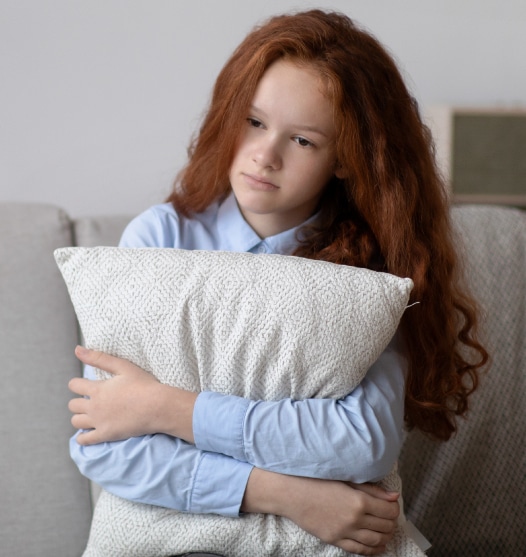 Sad teen girl sitting holding a pillow