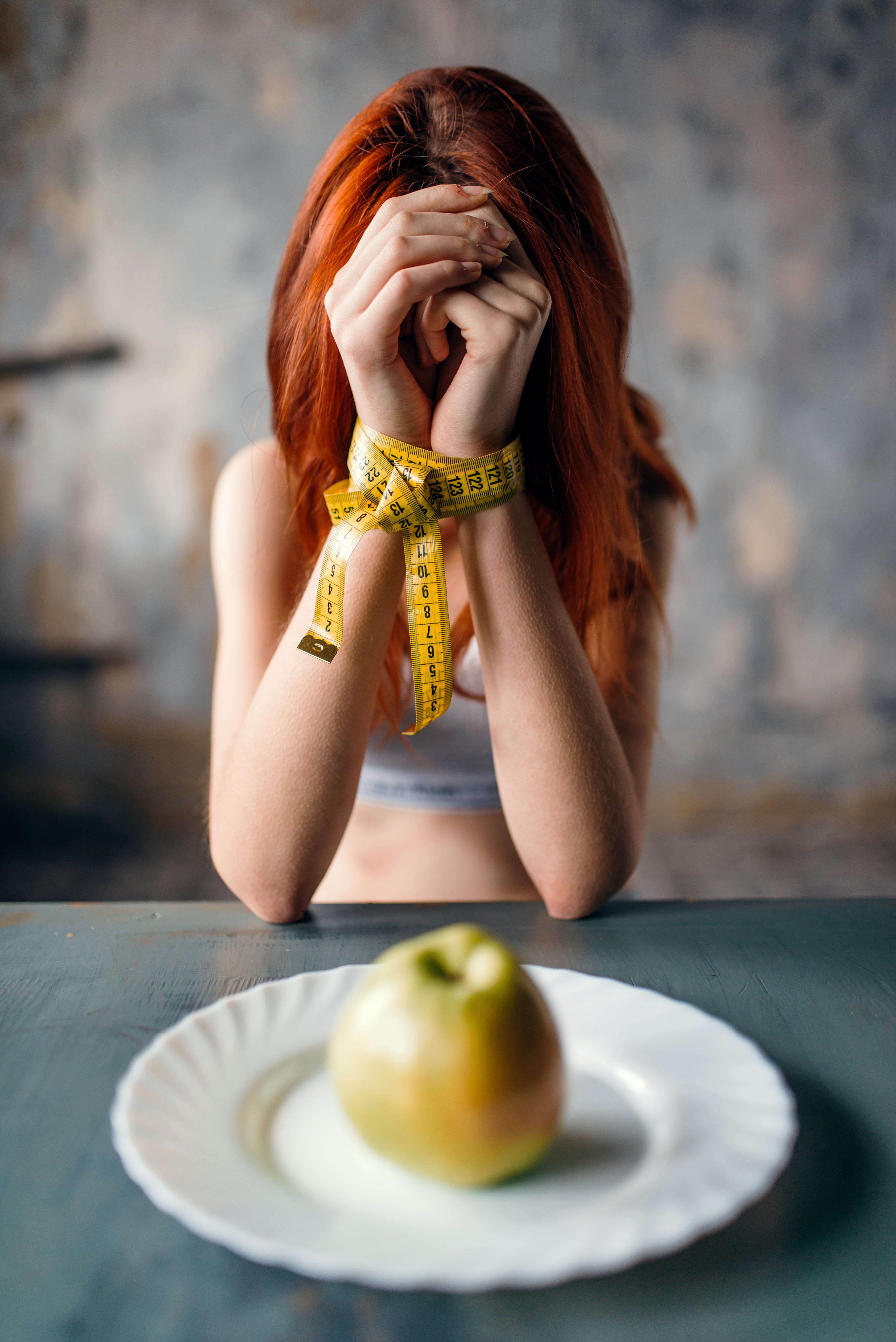 Womans hands are tied with measuring tape with an apple in the front