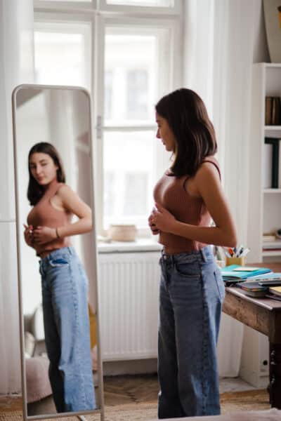 Teen girl looking in the mirror to her body figure